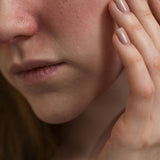 Lower portion of a womans face with her hands touching her cheek.