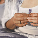 Close-up of hands holding a purple flower with a blurred background