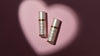 Two white skincare bottles sitting inside a beam of light that is in the shape of a heart
