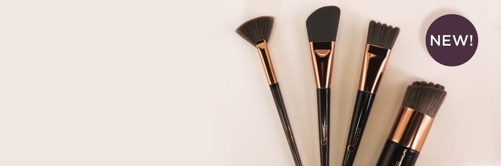 Set of makeup brushes with black bristles and rose gold handles on a white background, featuring a 'NEW!' label.