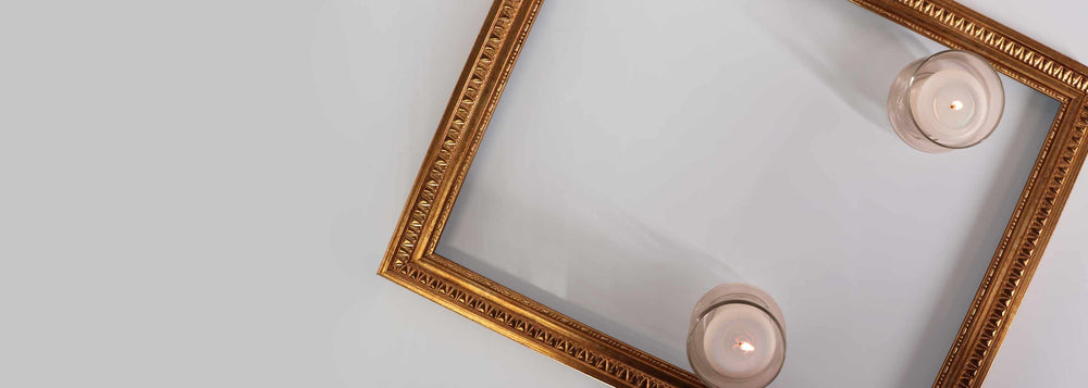 Decorative gold frame with two small candles on a light background