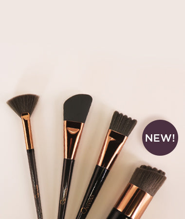Set of makeup brushes with black bristles and rose gold handles on a light beige background, featuring a 'NEW!' label.