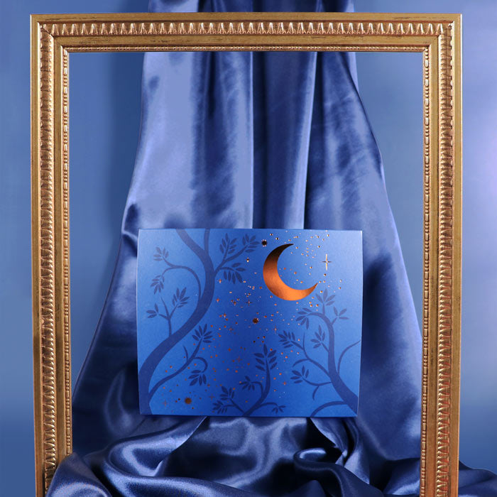 Blue card with a gold crescent moon design on a blue fabric background