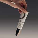 Osmosis Revive Hand Treatment tube held by a hand against a dark background