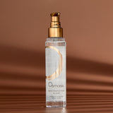 Osmosis Skin Perfection Elixir in a clear bottle with a gold pump dispenser, set against a warm brown background with soft shadows.